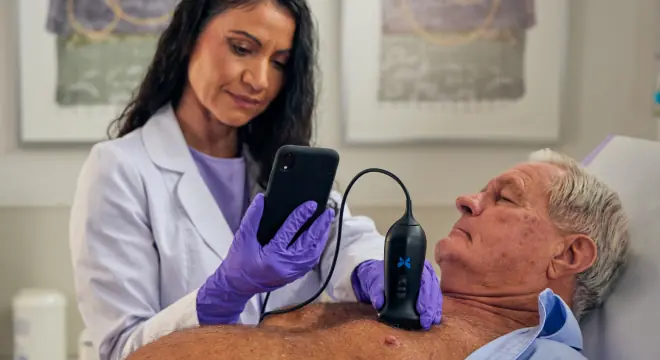 Clinician scanning a patient's chest with a Butterfly probe and smartphone